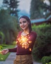 一位女子在花园里手持烟花，微笑着享受节日的户外时光
