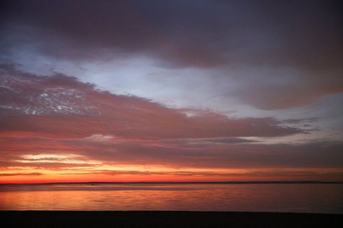 Free Breathtaking view of a vibrant sunset over a tranquil sea with colorful skies. Stock Photo