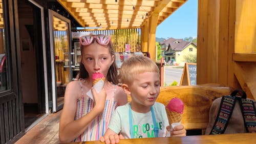 Children Enjoying Pink Ice Cream in the Summer Sun - Happy Kids' Summertime Treat Outdoors