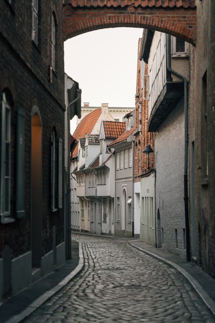 Quaint cobblestone alley with historic houses in Lübeck, Germany, showcasing medieval architecture.