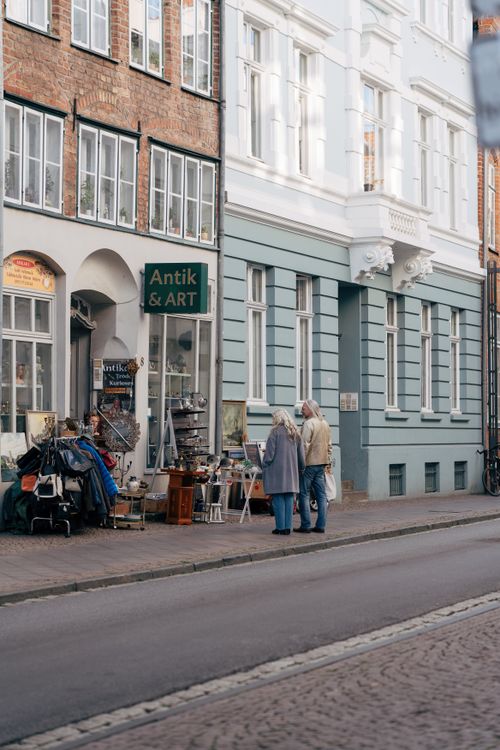 Free Elderly couple exploring an antiques shop on a charming street in Lübeck, Germany. Stock Photo