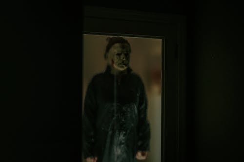 A Person in a Scary Halloween Costume Standing behind the Window 