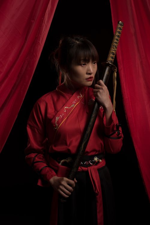 Free Studio portrait of an Asian woman in traditional samurai attire holding a sword. Stock Photo