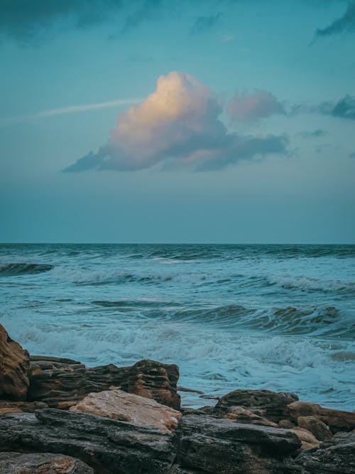 View of a Rocky Shore and Wavy Sea at Sunset