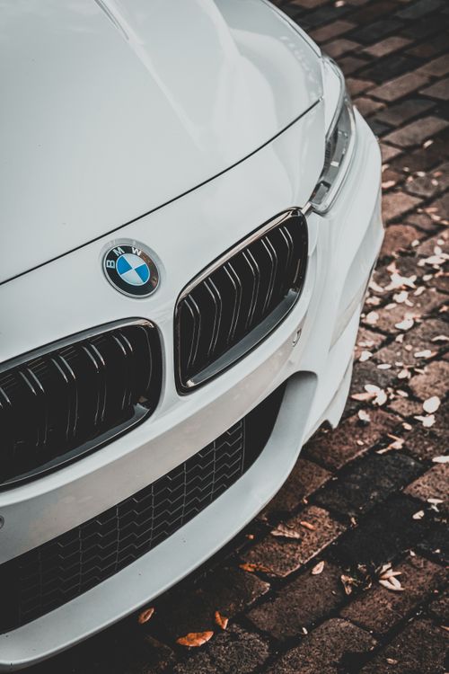 Free Detailed view of a white BMW sports car grill and emblem on a cobblestone street. Stock Photo