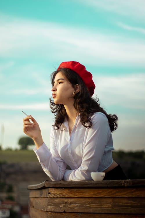 Woman in Hat and White Shirt Smoking Cigarette