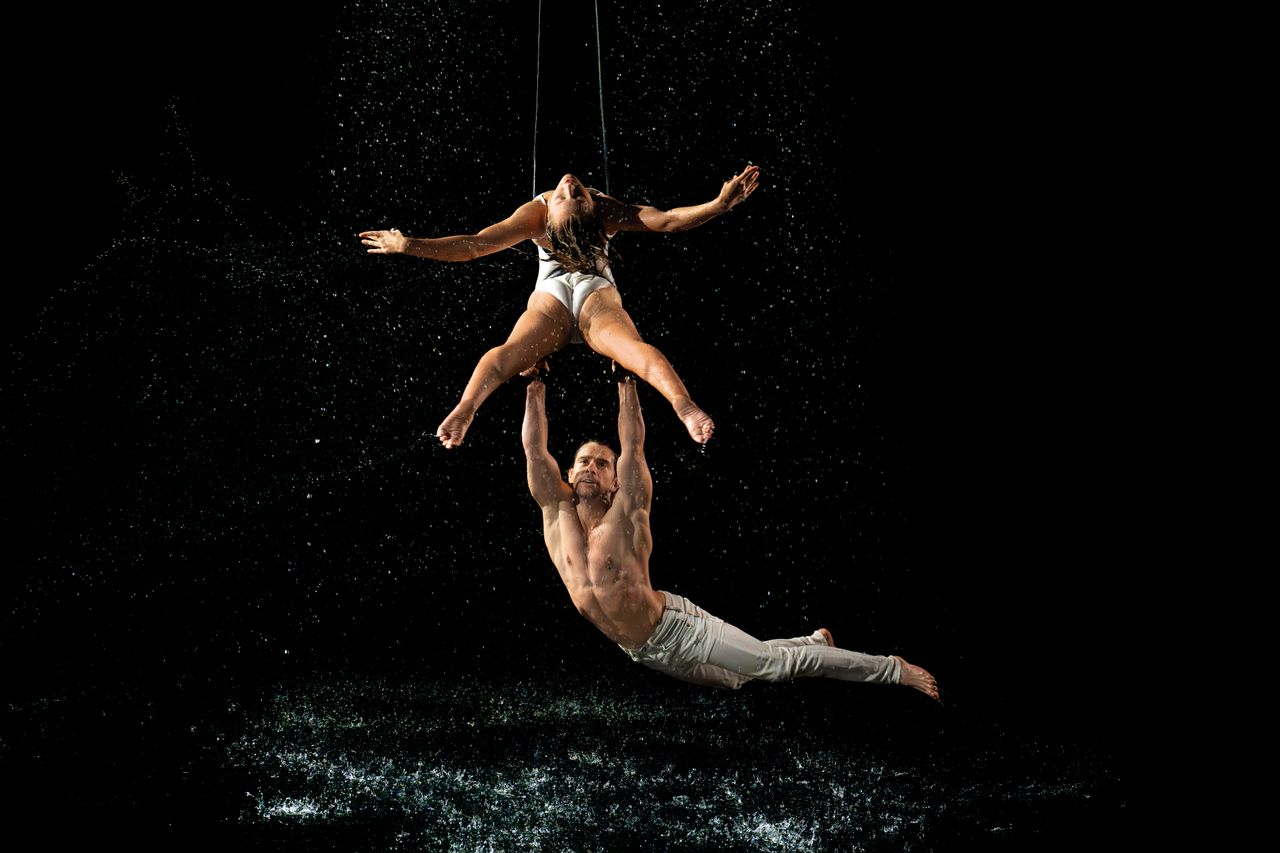 a mesmerizing duo performs aerial acrobatics amidst splashing water on