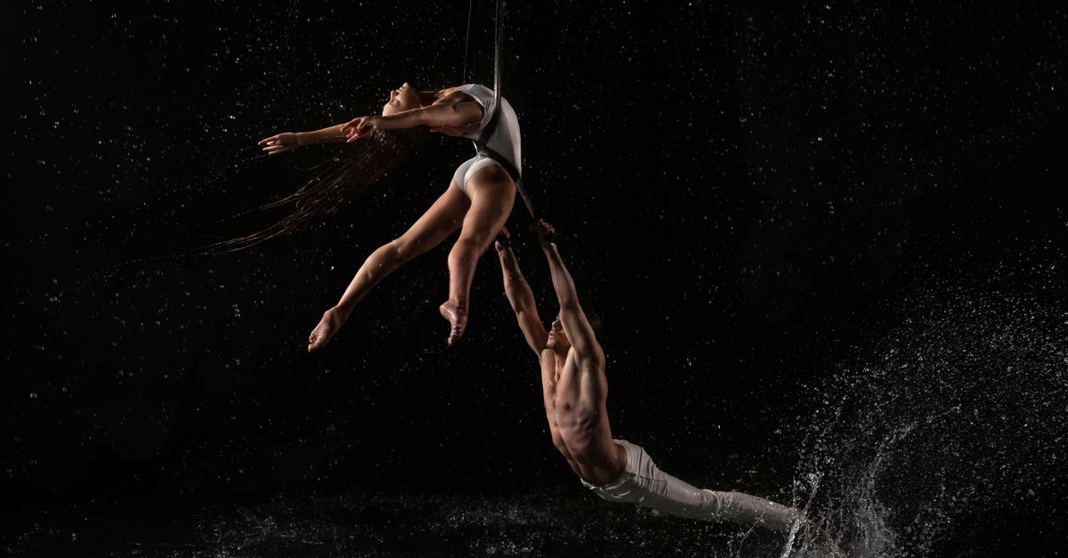 Captivating aerial dance with dynamic water splashes against a dark background.