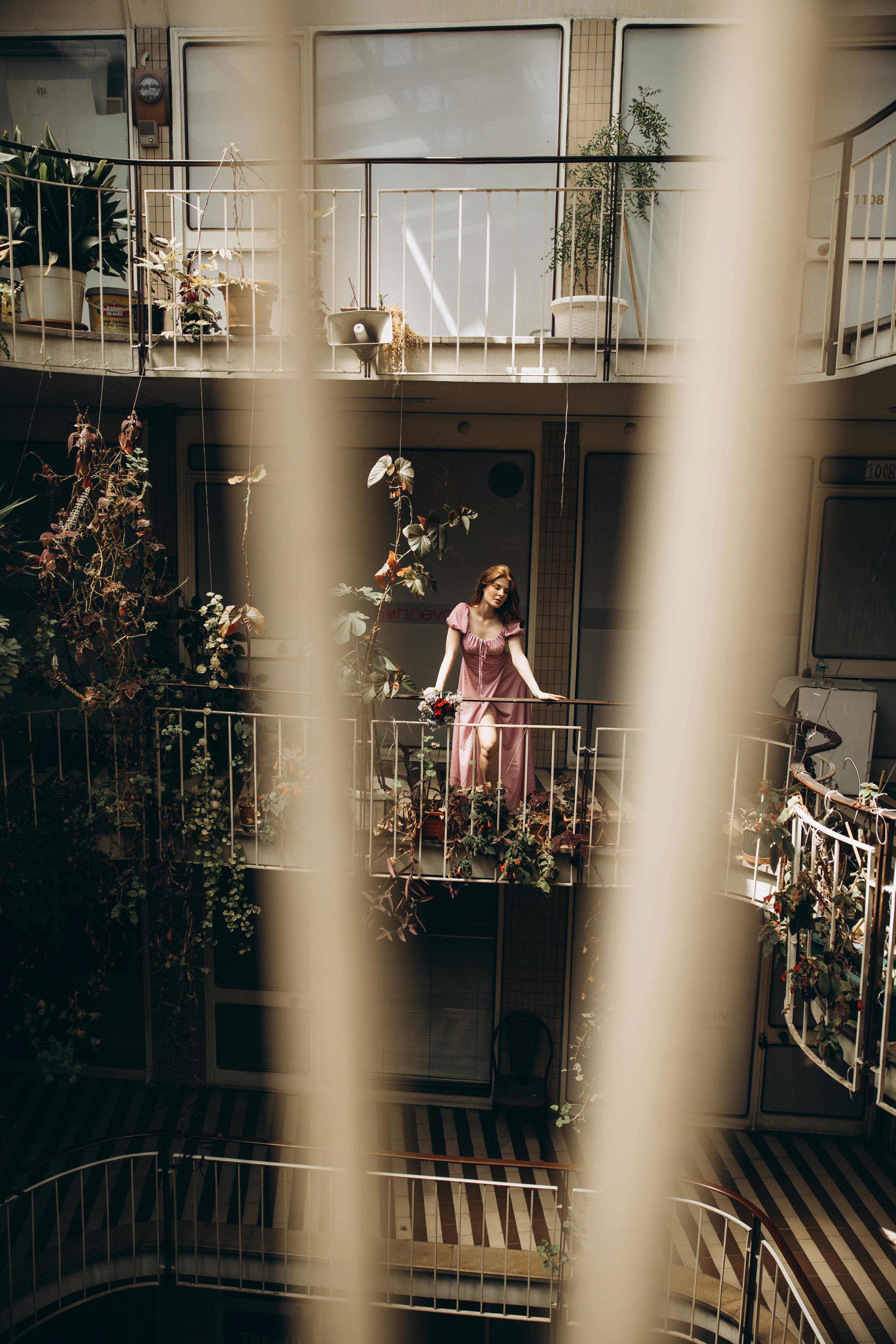 a woman in a pink dress is standing on the balcony