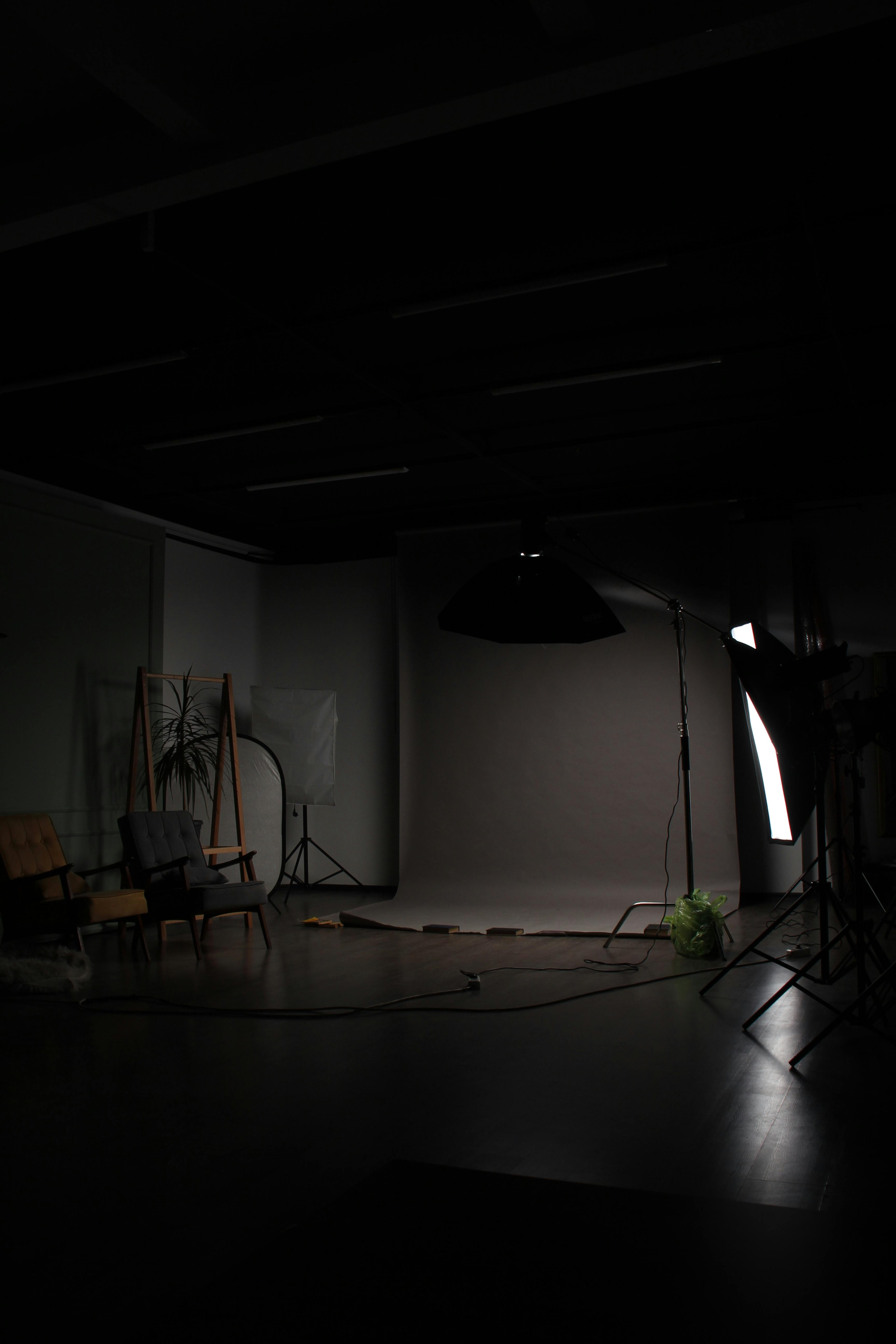 A dark and serene photo studio setup with chairs and lighting equipment.
