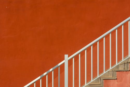 Staircase with White Wooden Railing against Red Wall
