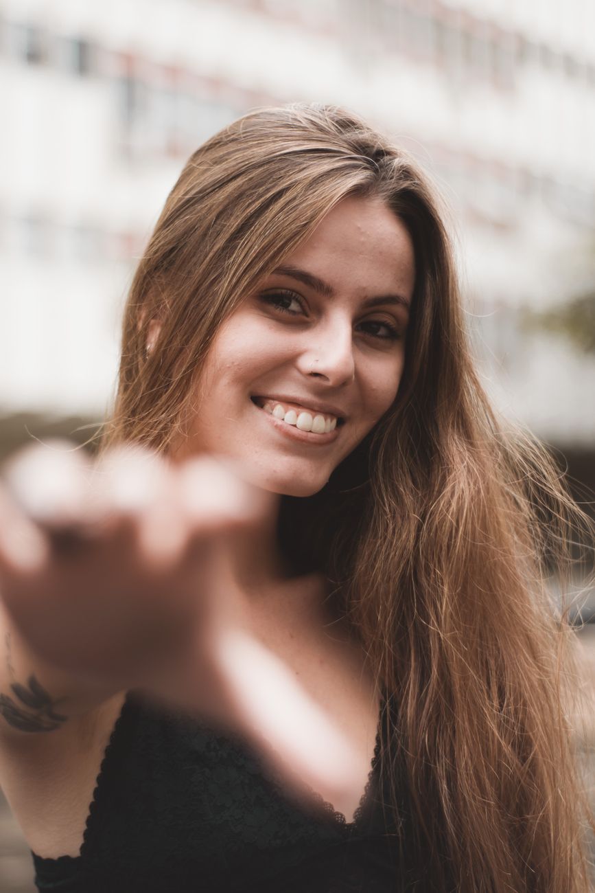 Portrait of a smiling young woman with long hair, enjoying a sunny day outdoors.