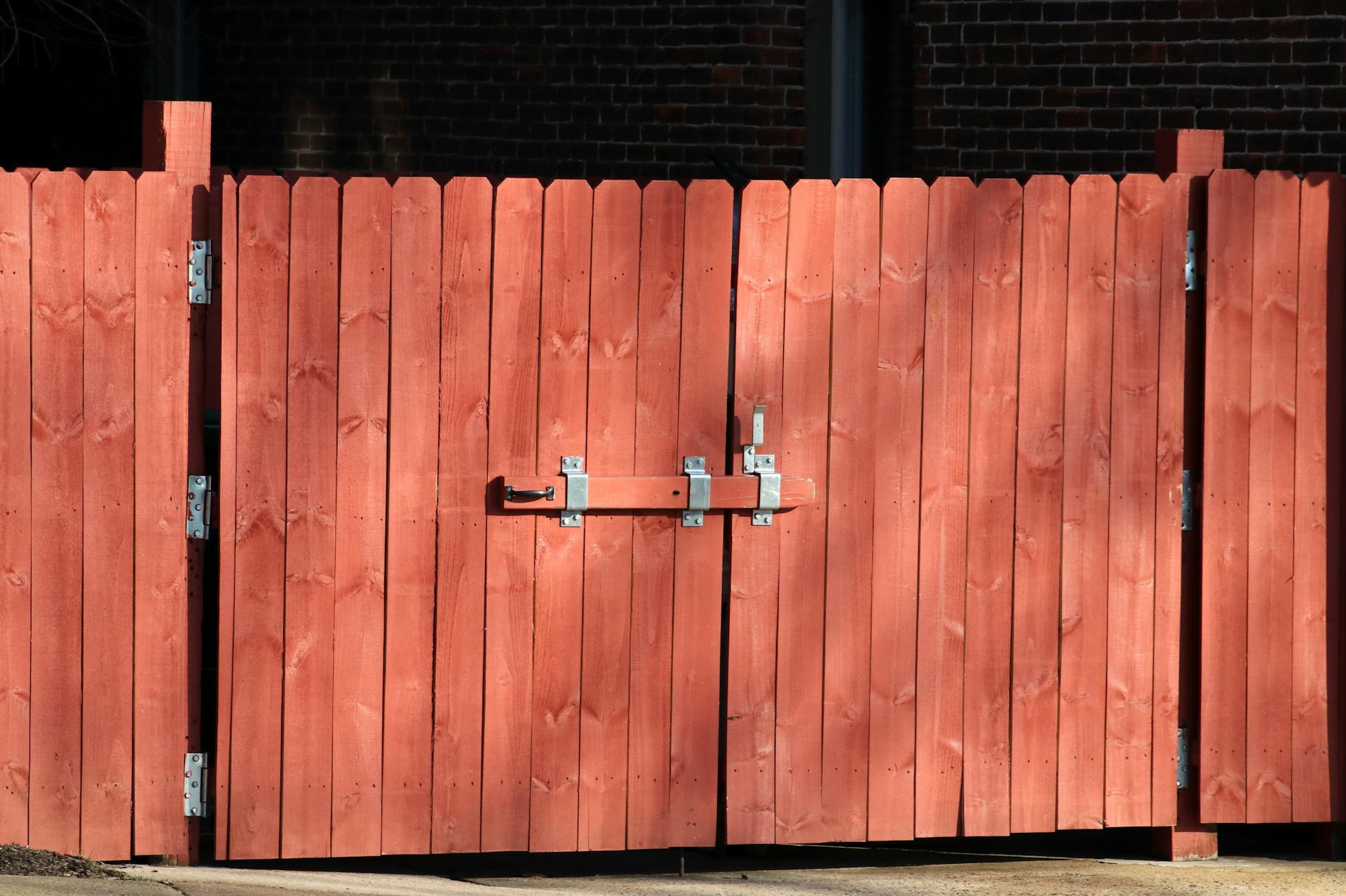 Rustic red wooden fence with a metal latch, ensuring safety and security outdoors.