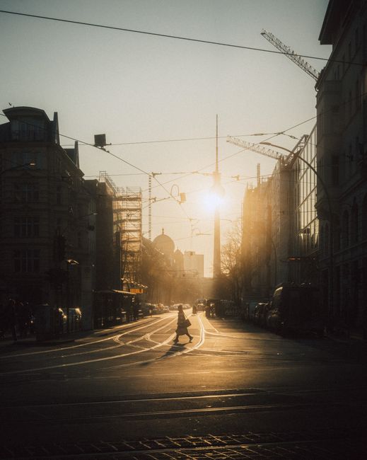 A stunning view of Berlin city streets during sunset with the iconic TV Tower in the background.