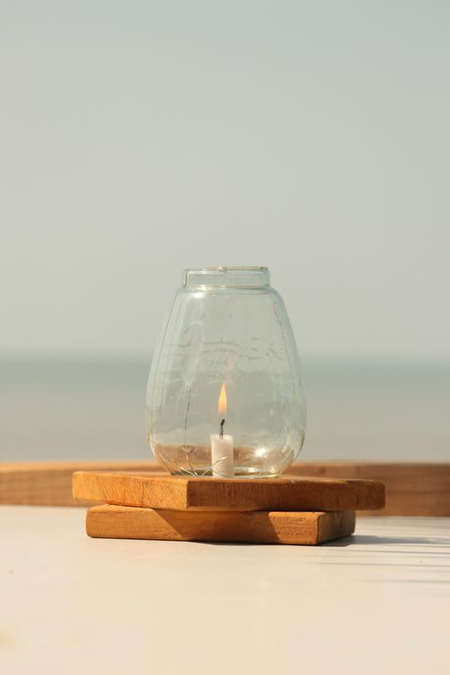 Free A serene beach setting with a candlelit glass jar creating a peaceful ambiance. Stock Photo