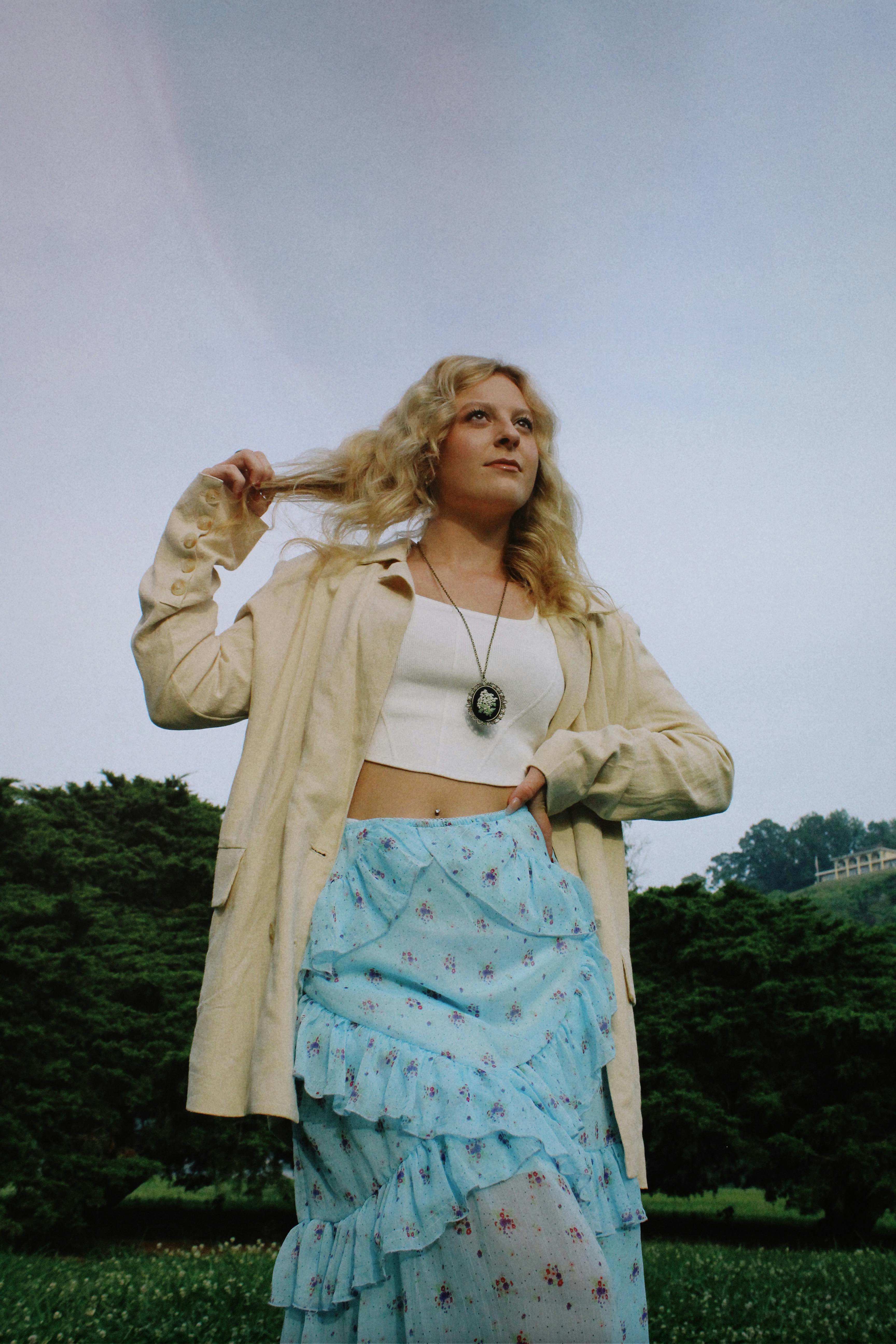 Blonde woman wearing a summer outfit, posing confidently in a scenic outdoor setting.