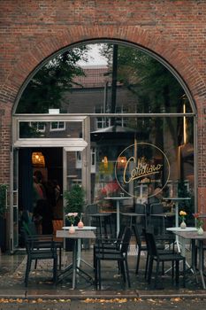 A cozy outdoor café entrance in Hamburg with tables and chairs on a rainy day.