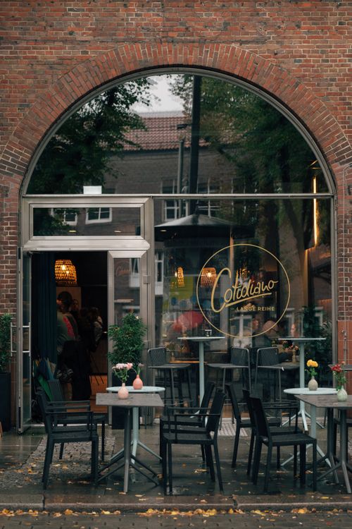 Free A cozy outdoor café entrance in Hamburg with tables and chairs on a rainy day. Stock Photo
