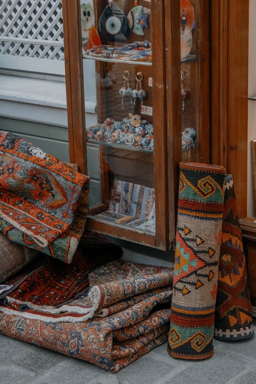 Patterned Rugs and a Cabinet with Figurines on a Sidewalk 