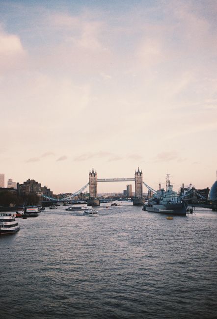 View of Tower Bridge over River Thames with boats at dusk in London, England.