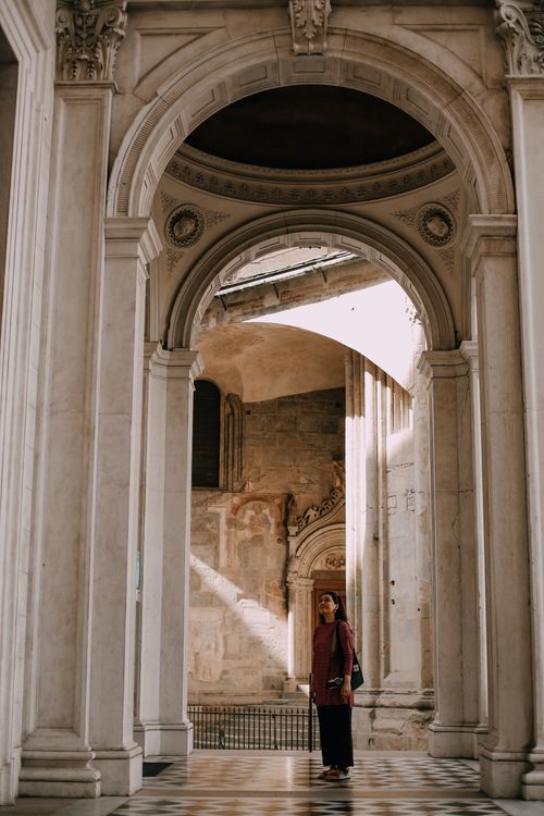 Free A young woman stands beneath the ornate arches of the Bergamo Cathedral, Italy. Stock Photo