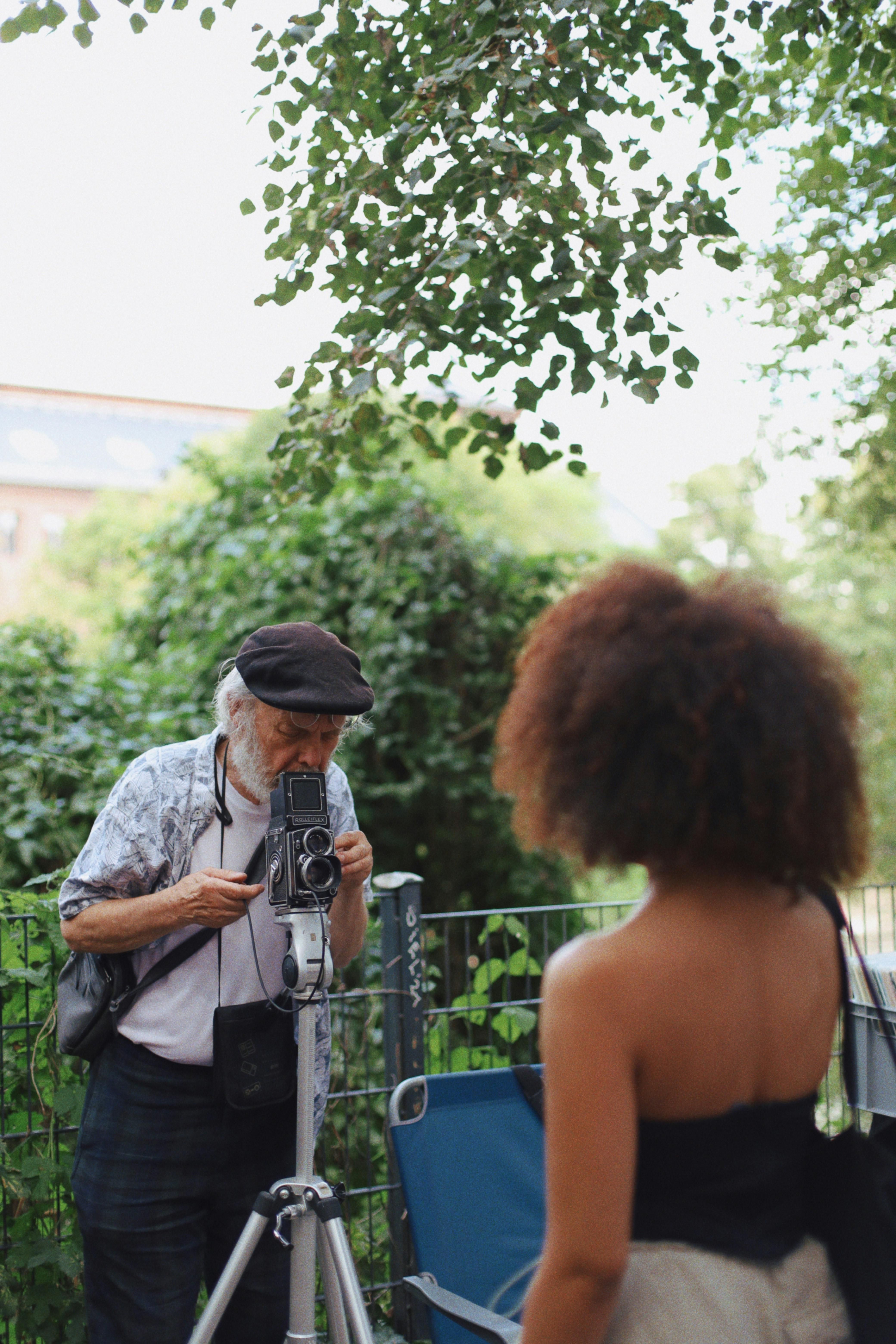 A photographer takes photos with an analogue camera in a Berlin park, featuring a woman model.