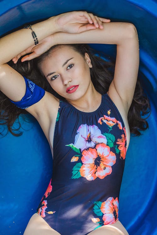 Free Photo of Woman in Blue Floral One-piece Swimsuit Lying Down With Hands over Head Stock Photo