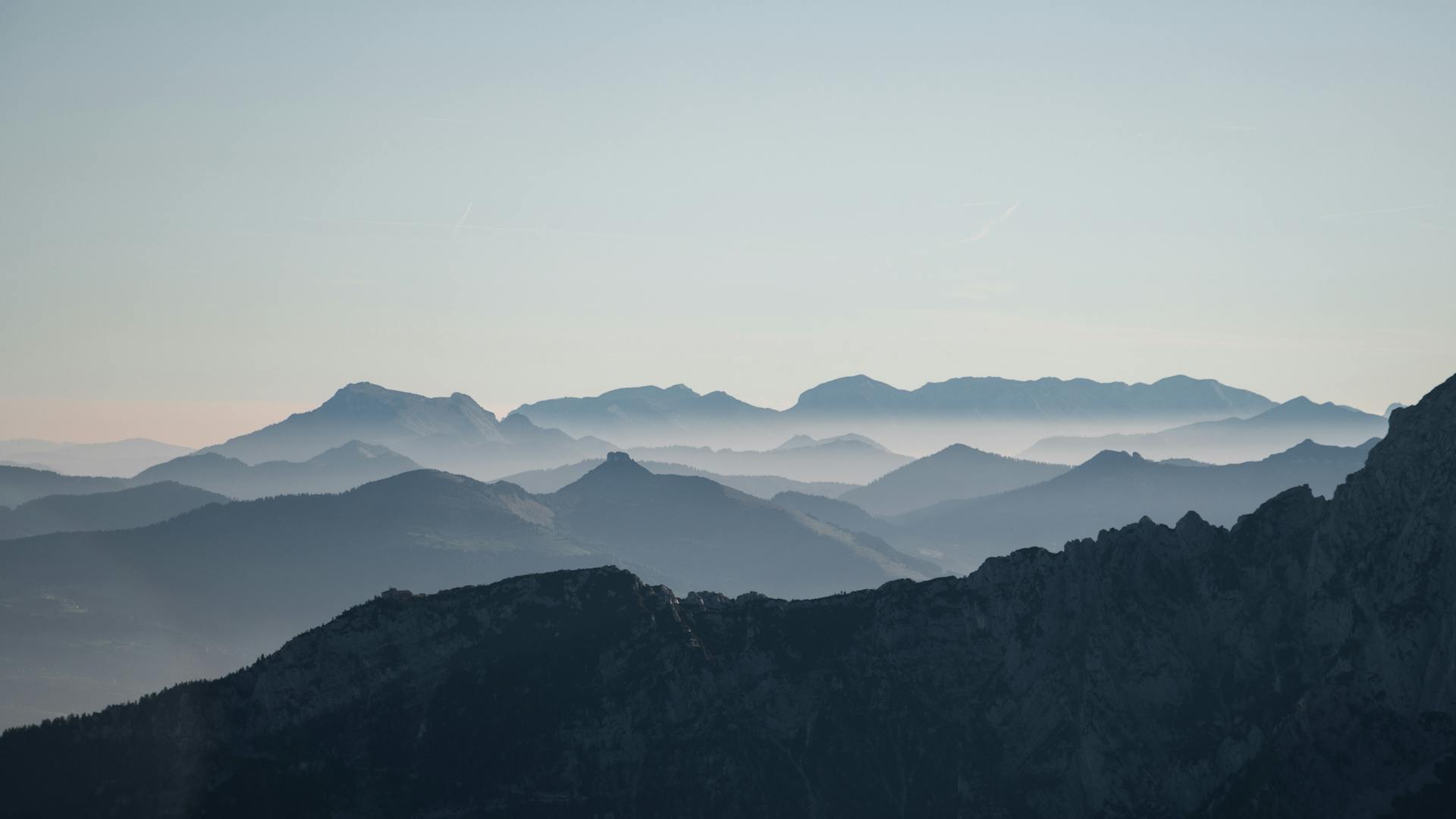 Serene morning view of the Bavarian Alps with misty layers and clear sky.