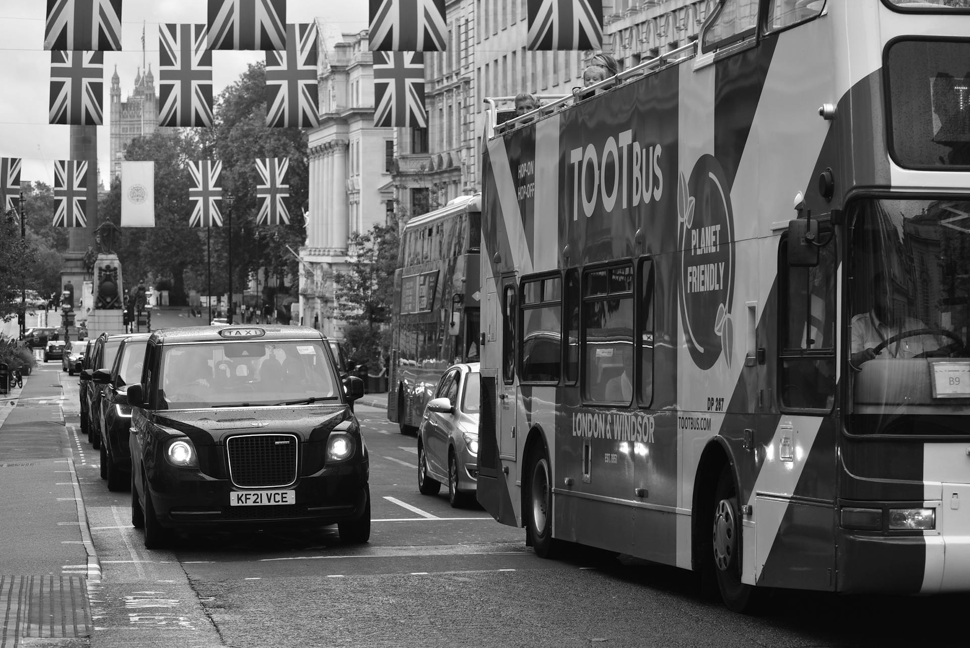 Iconic London street scene with double-decker buses, taxis, and Union Jack flags, showcasing urban travel.