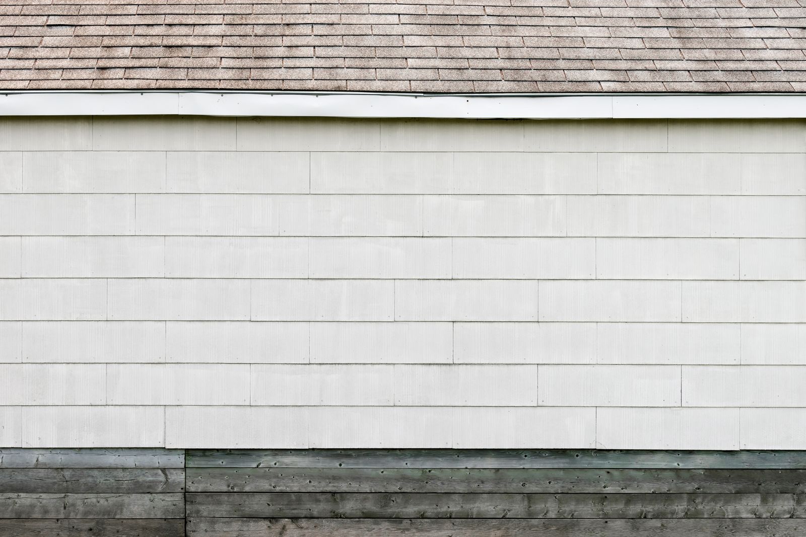 Minimalist home exterior with white siding and a shingled roof, clean lines
