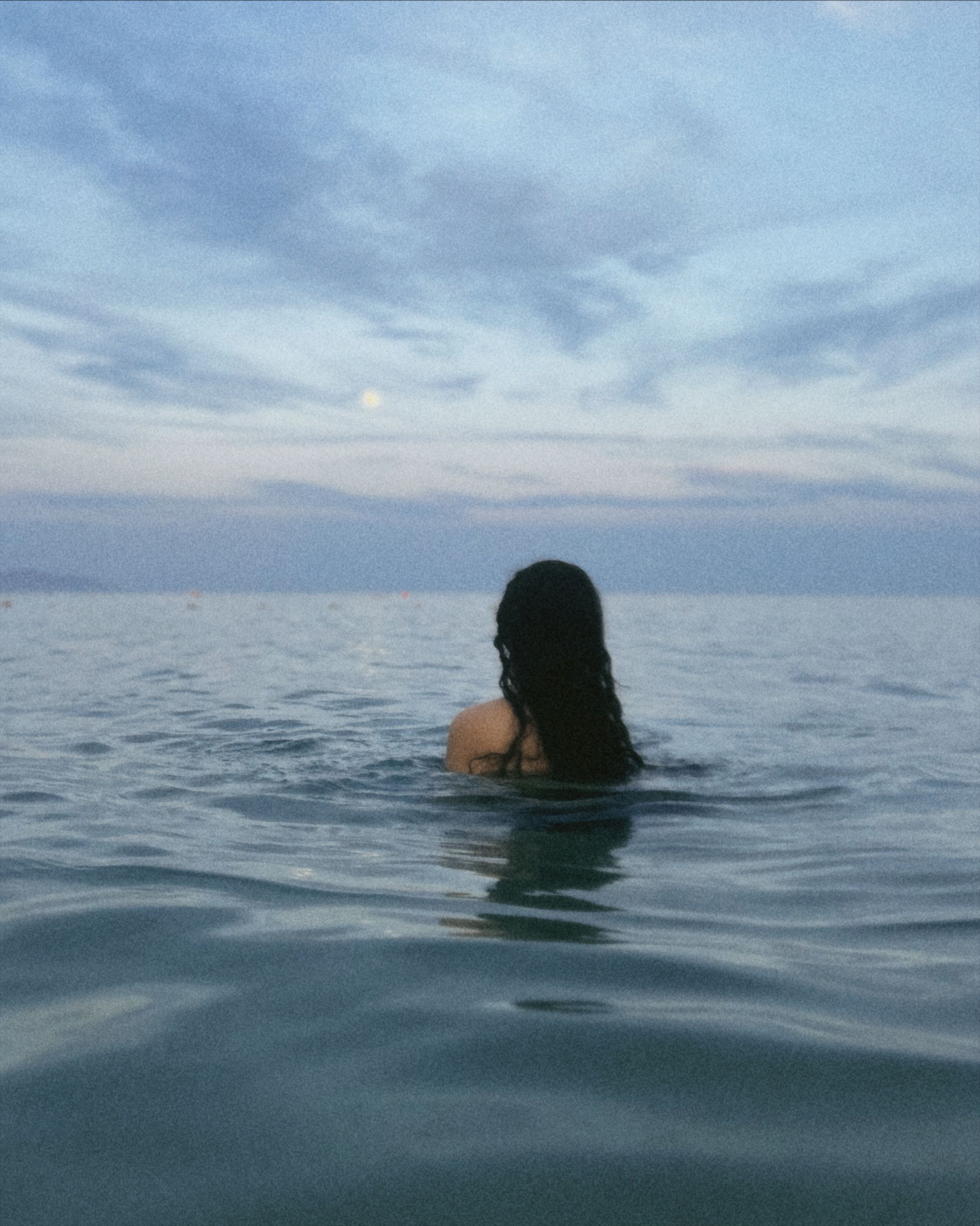 A serene moment of a woman swimming in the calm sea at sunset in Sharm El-Sheikh, Egypt.