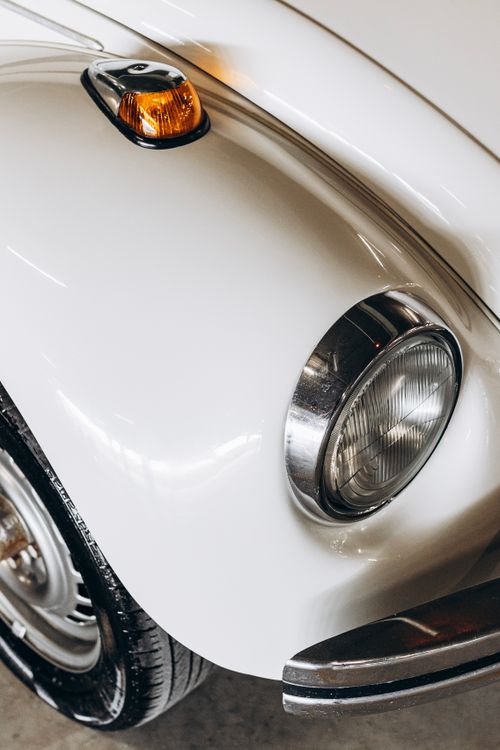 Free A detailed close-up of a classic white vintage car showcasing its headlight and turn signal. Stock Photo