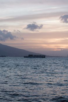 A tranquil ship sailing at sunset with stunning ocean and sky landscape.