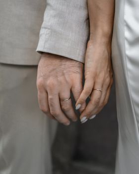 Intimate shot of a couple holding hands, showcasing wedding rings on their special day.