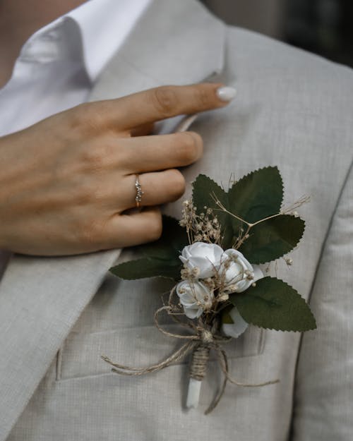Hand of a Woman Fixing the Collar of a Mans Suit Jacket and a Boutonniere