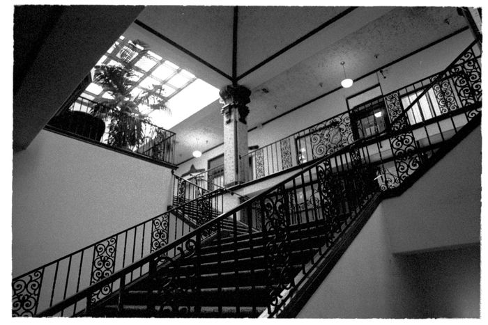 Ornate ironwork staircase beneath a glazed atrium roof — photo by Katherine Bowers on Pexels