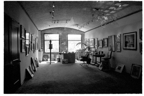 Free Elegant black and white art gallery interior in Santa Ana, featuring various framed artworks and a central window view. Stock Photo