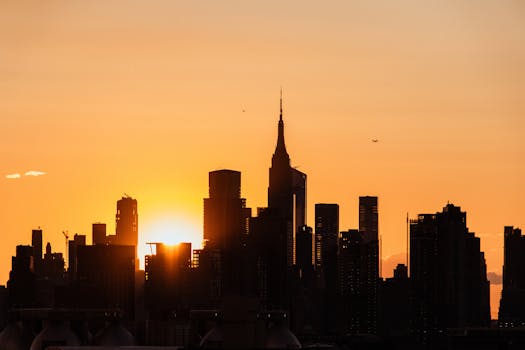 Dramatic silhouette of New York City's skyline against a vibrant sunset.