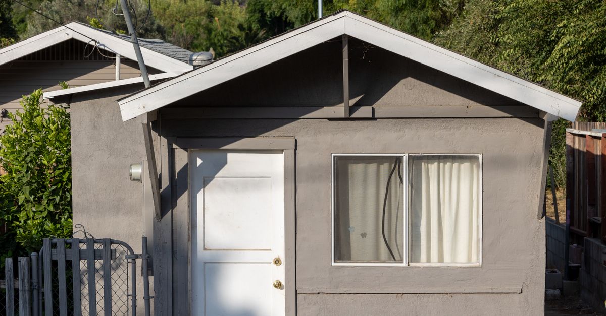 Charming small house with a sunlit facade and a simple door in a quiet village setting.