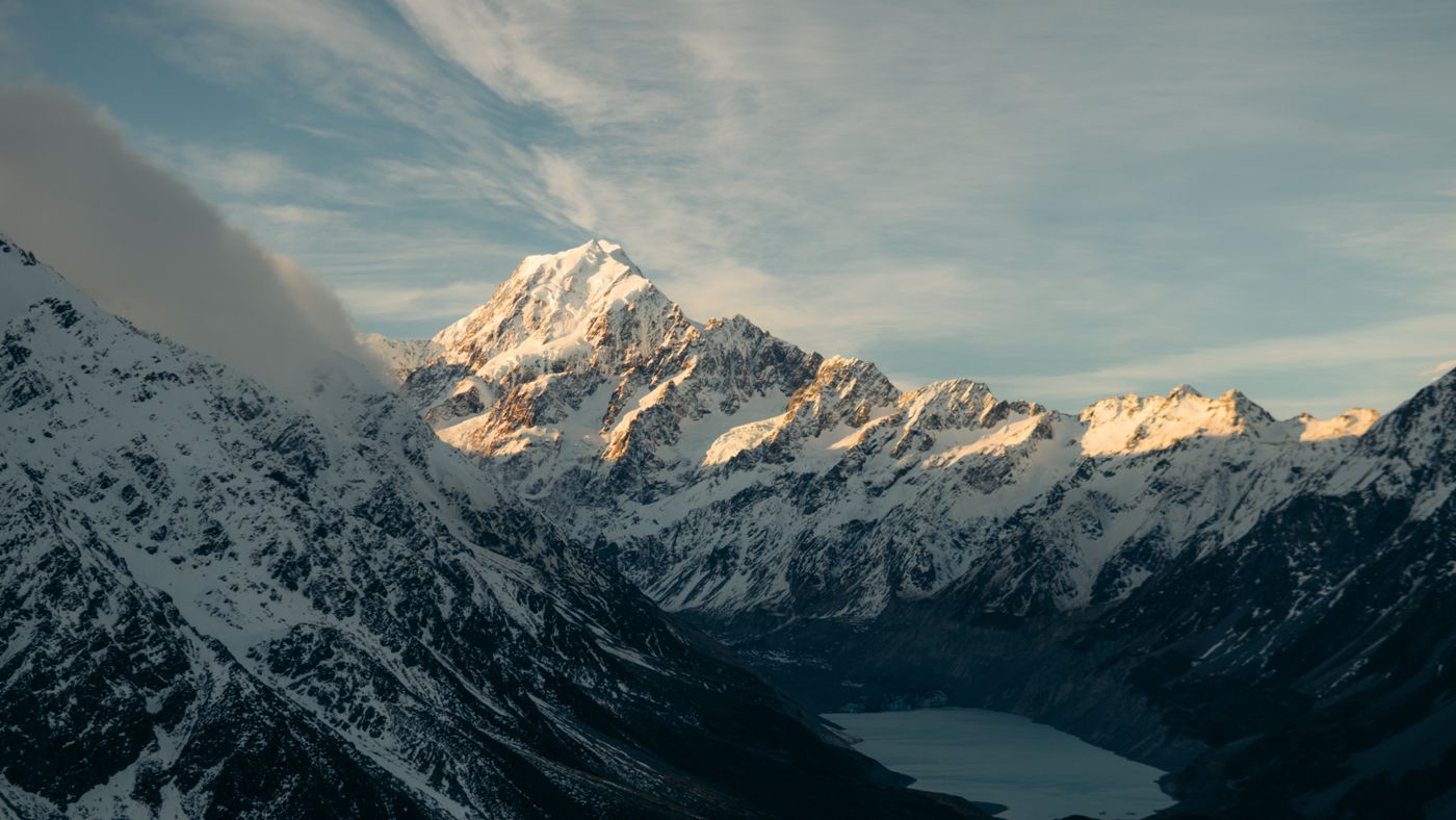 Snowcapped peaks of Aoraki, Mount Cook, above a lake in New Zealand's Southern Alps at sunrise