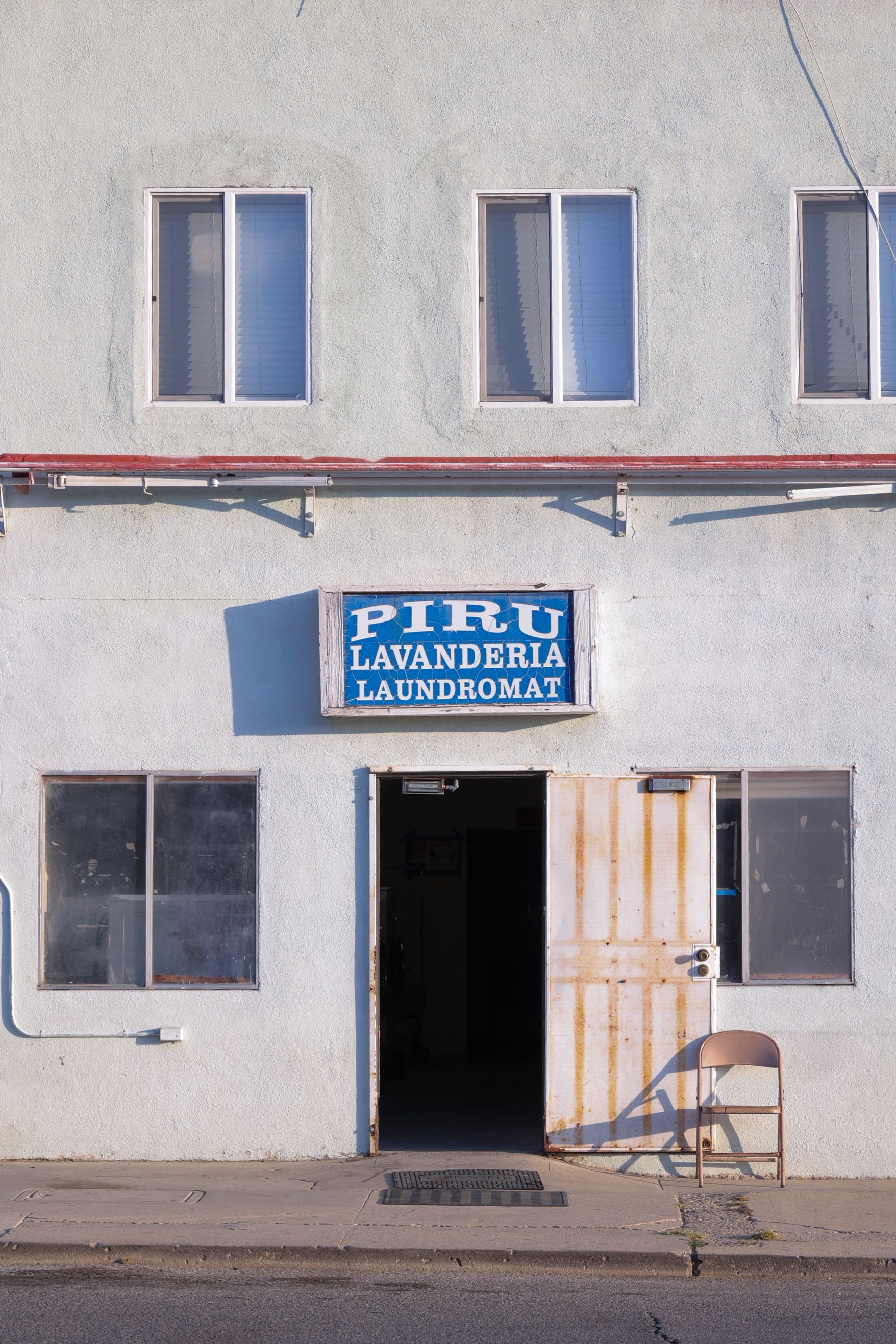 Street view of Piru Lavanderia Laundromat entrance with open door and windows.
