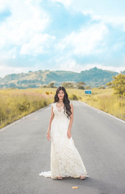 Bride Standing in the Middle of an Asphalt Road in the Countryside