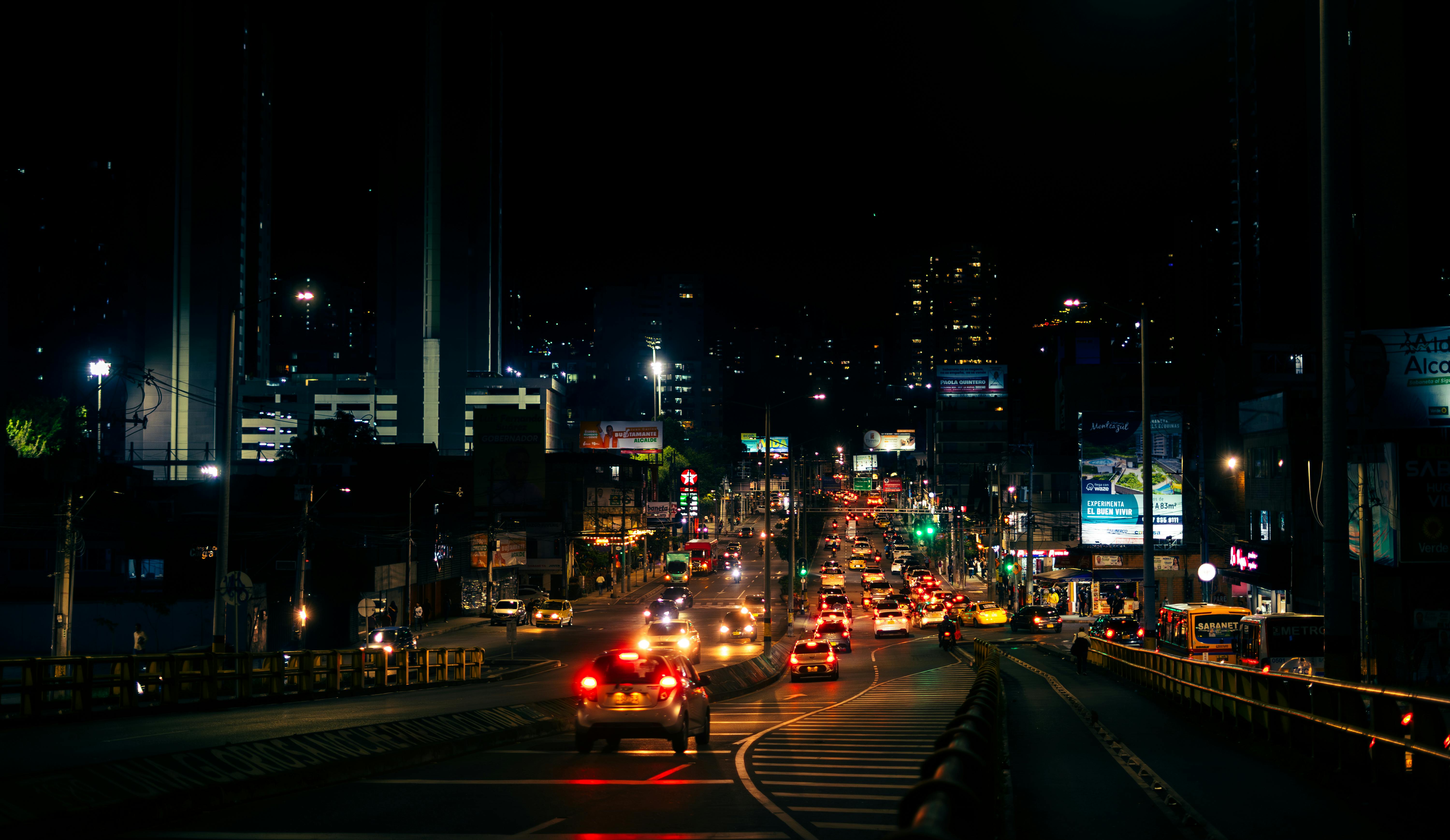 Busy city street in Sabaneta, Antioquia at night with vibrant urban traffic and illuminated buildings.
