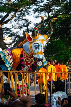 Vibrant bull sculpture showcased during a lively cultural festival parade outdoors.
