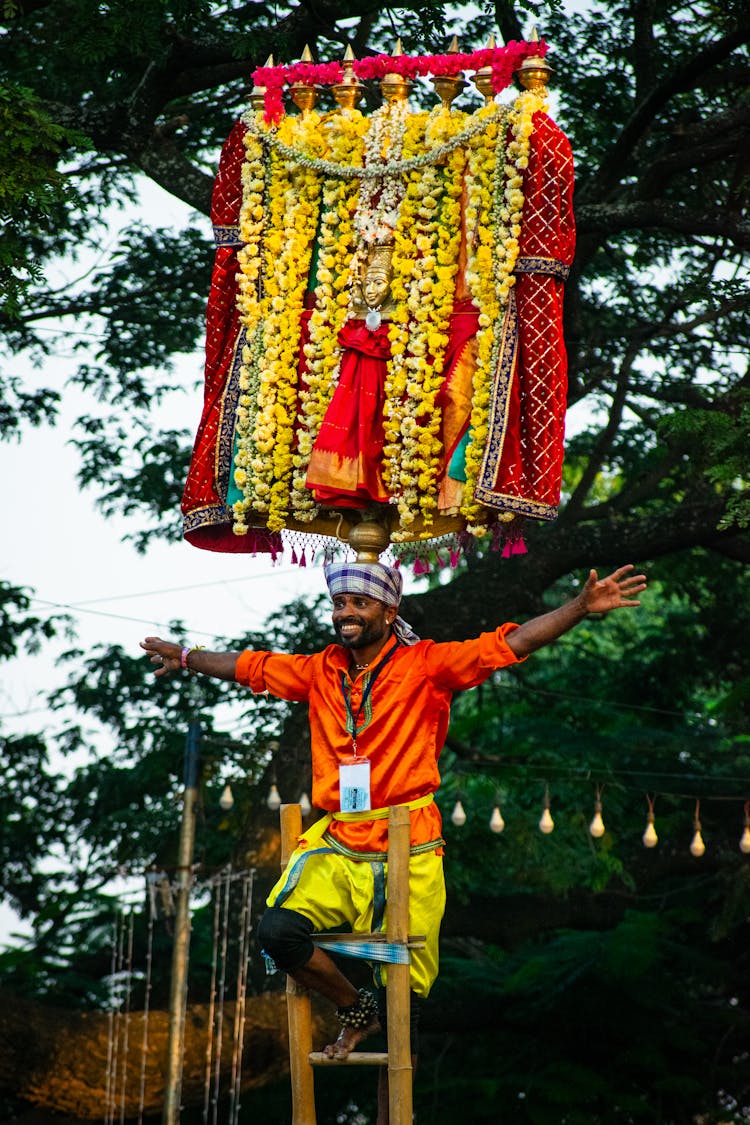 Smiling Man On Top Of A Ladder Under A Flowery Banner