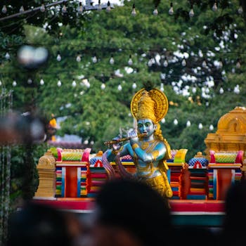 Vibrant outdoor celebration featuring a Krishna statue amidst festive lights.