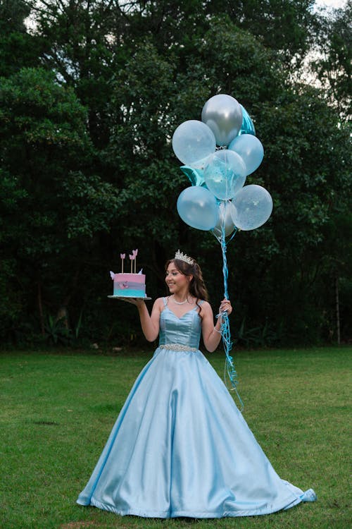 Woman in a Princess Dress Holding Balloons and a Birthday Cake