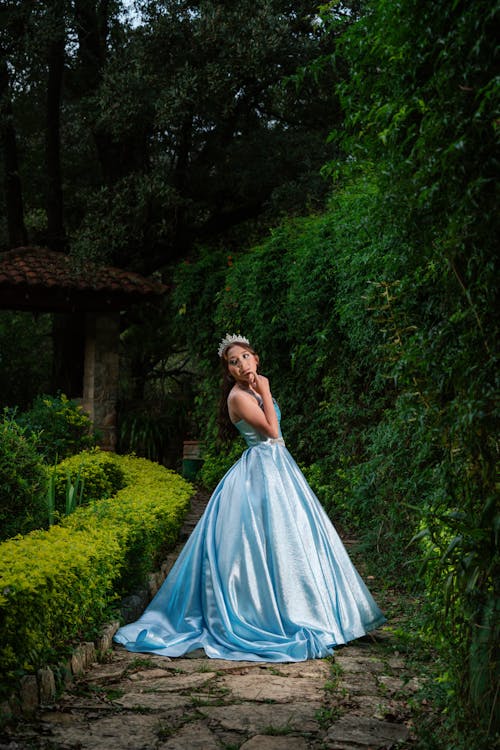 Woman in a Princess Dress Standing on a Garden Path