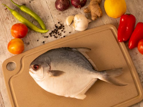 Free A Fish on a Cutting Board with Vegetables Lying Around  Stock Photo