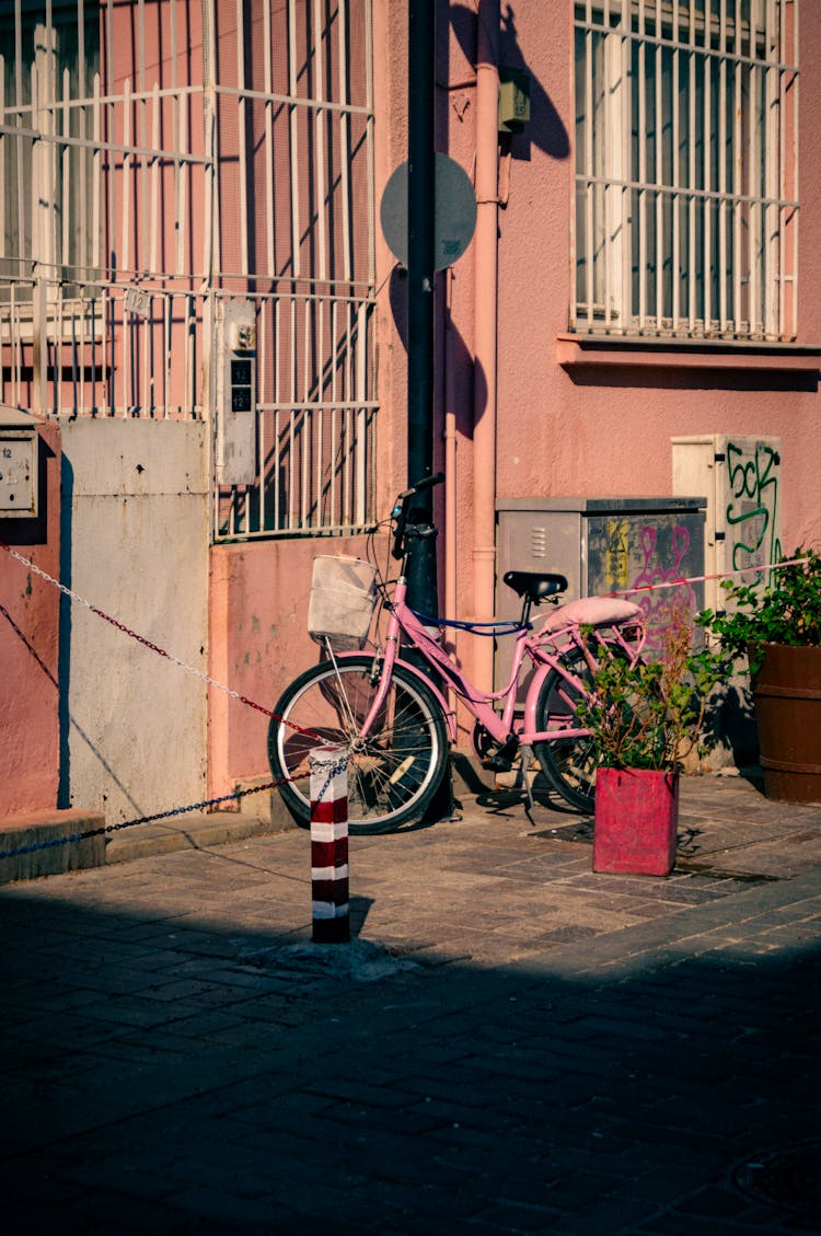 A Bicycle Standing In Front Of A Pink House 